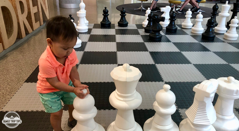 child playing with chess pieces at austin central library